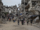 Palesztinok gyalogolnak lebombázott épületek között a Gázai övezet középső részén lévő Bureidzs menekülttáborban 2024. szeptember 17-én