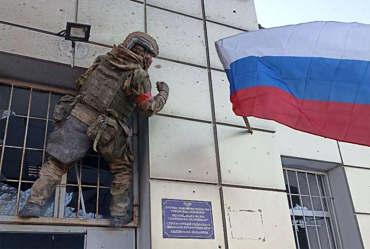 Orosz katona tűz ki zászlót egy avgyijivkai épületre - a várost kénytelenek voltak feladni az ukránok 