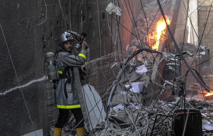 Palesztin tűzoltók egy megsemmisült lakóépület lángjait oltják Gázában, miután az izraeli hadsereg ismét több légicsapást hajtott végre a Gázai övezetben. Fotó: MTI/EPA/Mohamed Szaber