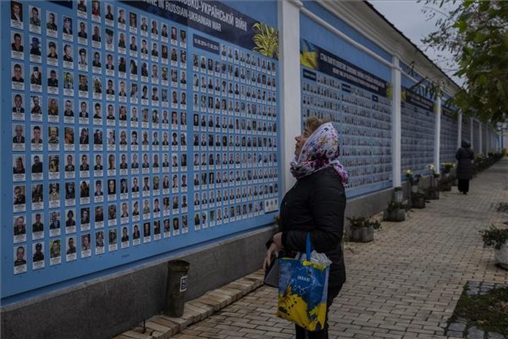 Az orosz-ukrán háborúban elesett ukrán honvédők emlékfalát nézi egy nő egy kijevi utcán 2022. november 7-én, az Ukrajna elleni orosz háború idején. Fotó: MTI/AP/Bernat Armangue