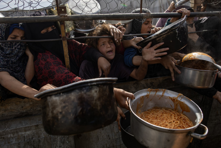 Palesztin belföldi menekültek főtt ételt kapnak egy jótékonysági szervezet ételosztásán a Gázai övezet déli részén fekvő Hán-Júniszban 2026. február 7-én