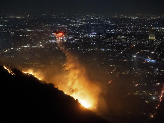 Erdőtűzre dobnak le vizet helikopterrel Los Angeles Hollywood Hills városrészére 2025. január 8-án. Gavin Newsom kormányzó vészhelyzetet hirdetett ki a kaliforniai erdőtüzek miatt, Santa Monicában kitelepítést rendeltek el. A hatóságok eddig öt ember halálát erősítették meg. Los Angeles környékén 3-4 helyen ég a bozót, a lakott területekre átterjedt lángok ezernél több házat emésztettek fel. 