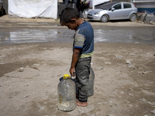 . A 2024. augusztus 29-i képen egy palesztin kisfiú megpihen vízzel töltött palackok cipelése közben a Gázai övezet középső részén fekvő Deir al-Balah városban létesült belföldi menekülttáborban. 