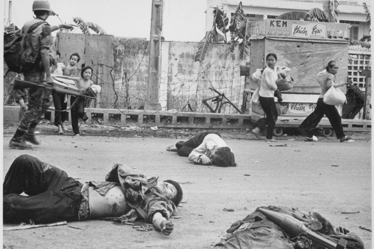 Dél-vietnámi katona mutat utat menekülő civileknek a Tet-offenzíva idején, az előtérben Vietkong katonák holttestei. Az ilyen képek nem segítettek meggyőzni az amerikai közvéleményt, hogy a dolgok jól mennek Vietnámban. Fotó: Wikimedia