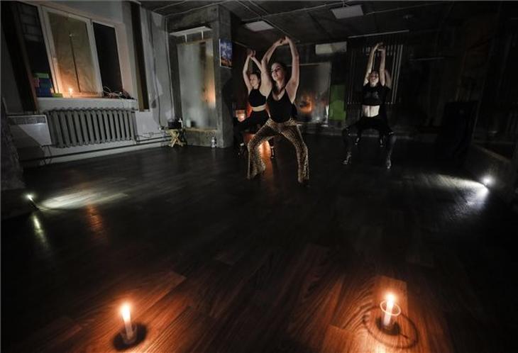 Modern táncot gyakorló nők áramszünet idején egy kijevi fitnessklubban 2022. október 24-én. A villamos áramot termelő ukrajnai létesítményeket érő orosz támadások miatt tervezett kimaradások vannak az ukrán fővárosban. Fotó: MTI/EPA/Szerhij Dolzsenko