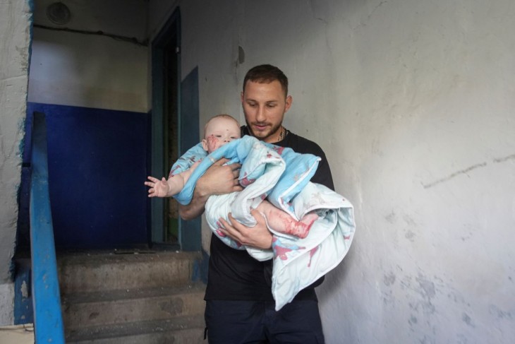 Csecsemőt menekít ki egy férfi egy orosz rakétatámadásban találatot kapott lakóépületből a délkelet-ukrajnai Harkivi területen levő Pervomajszkijban 2023. július 4-én. Az ukrán hatóságok szerint a légicsapásban legkevesebb harmincegyen megsebesültek, köztük kilenc gyermek. Fotó: MTI/AP