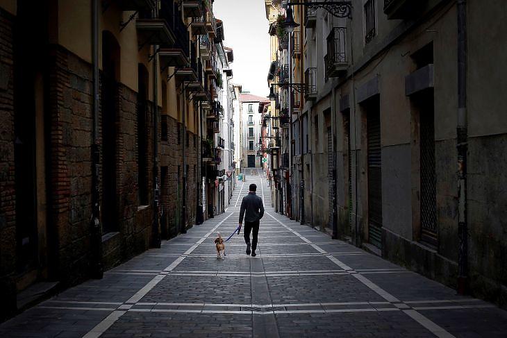 Egy férfi sétáltatja a kutyáját egy üres utcán Pamplonában (Baszkföld, Spanyolország) 2020. március 28-án. EPA/VILLAR LOPEZ