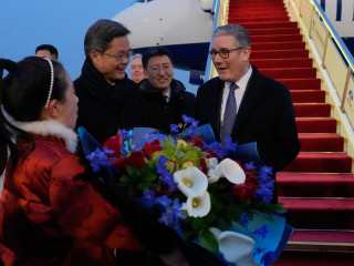 Keir Starmer brit miniszterelnököt (j) virággal köszöntik, miután megérkezett a pekingi repülőtérre 2026. január 28-án. MTI/AP pool/Kin Cheung