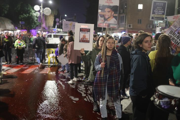 A túszok kiszabadítását követelő tüntetők Jeruzsálemben, Benjámin Netanjahu izraeli kormányfő rezidenciája előtt 2024. január 22-én. A tiltakozók vért szimbolizáló piros vizet öntöttek az utcára