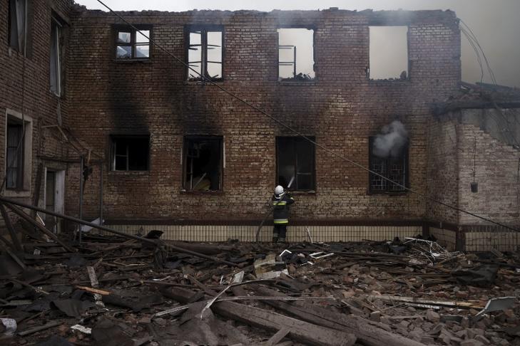 Tűzoltók oltják egy vendéglátóipari iskola romjainak lángjait egy orosz támadás után Harkiv külvárosában. Fotó: MTI/AP/Felipe Dana