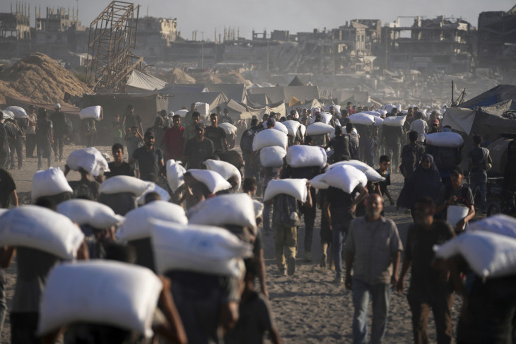 Humanitárius segélyként érkezett lisztet cipelnek palesztin emberek Gáza városába a Gázai övezet északi részéből 2025. július 31-én