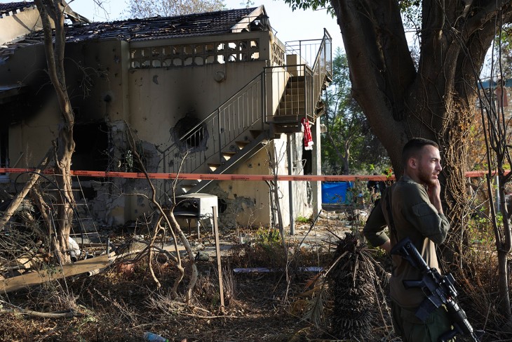 Egy izraeli katona a Be'eri kibucban 2023. október 25-én. A pusztítás nyomai borzalmasak, de a képen látható házon azt a hatalmas lyukat biztosan nem egy kézifegyver okozta - vajon akkor már élő civilek nem tartózkodtak az épületben? Fotó: MTI/EPA/Abir Szultan 