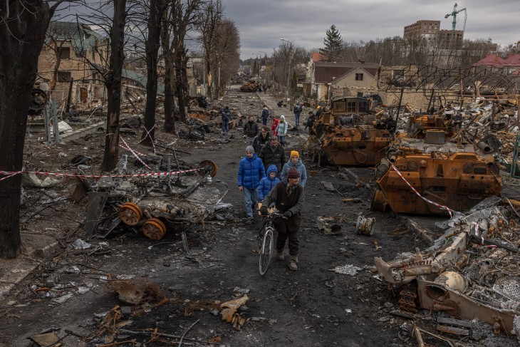 Helyi lakosok egy szétlőtt utcán az orosz haderőtől visszafoglalt Bucsában, Kijevtől északnyugatra 2022. április 6-án. Bucsa a háború egyik szimbóluma lett, az orosz csapatok háborús bűnnel felérő mészárlást követtek el itt helyszíni vizsgálatok szerint. Fotó: EPA/ROMAN PILIPEY 