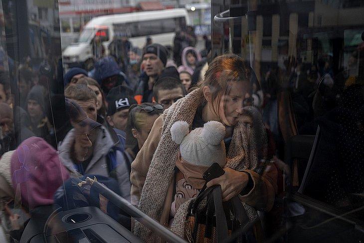 Gyermekét tartó nő felszáll egy buszra Kijevben, hogy elhagyja a várost 2022. február 24-én. (MTI/AP/Emilio Morenatti)
