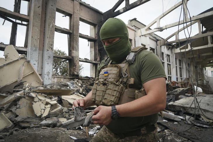 Ukrán katona rakétamaradványokkal a kezében a harkivi Nemzeti Műszaki Egyetem orosz légicsapásban megsemmisült tornatermében 2022. június 24-én. Fotó: MTI/AP/Andrii Marienko