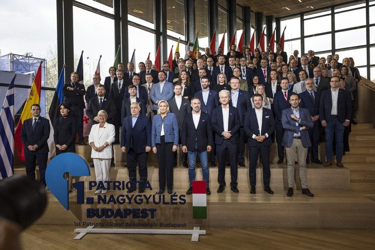 Orbán Viktor miniszterelnök, a Fidesz elnöke (első sor, b4) az 1. Patrióta Nagygyűlésen a Millenárison 2026. március 23-án. Mellette Petr Macinka cseh külügyminiszter (b), Maka Bochorishvili georgiai külügyminiszter (b2), Gál Kinga, a Patrióták Európáért európai parlamenti képviselőcsoport első alelnöke (b3), Marine Le Pen, a francia Nemzeti Tömörülés parlamenti frakcióvezetője (j5), Santiago Abascal, a spanyol VOX párt elnöke (j4), Geert Wilders, a holland Szabadságpárt (PVV) vezetője (j3), Matteo Salvini, a kormányzó olasz Liga párt elnöke, miniszterelnök-helyettes (j2) és Tom Van Grieken, a Flamand Érdek (Vlaams Belang) belga jobboldali párt elnöke (j)
