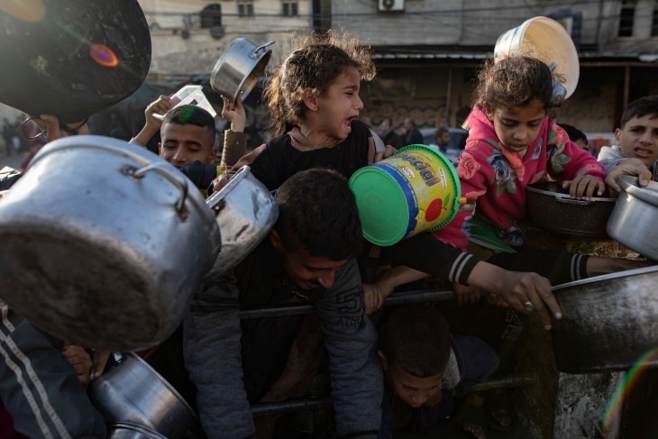 Kétségbeesett gyerekek várnak a segélyszervezetek ételosztására a Gázai övezet déli részén fekvő Rafahban 2024. március 14-én. 
