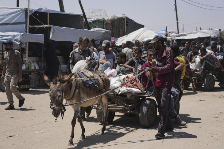 Az amerikai hátterű Gázai Humanitárius Alap segélyszervezet által kiosztott segélyt visznek palesztinok a Gázai övezet déli részén fekvő Rafahban 2025. június 16-án.