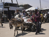 Az amerikai hátterű Gázai Humanitárius Alap segélyszervezet által kiosztott segélyt visznek palesztinok a Gázai övezet déli részén fekvő Rafahban 2025. június 16-án.
