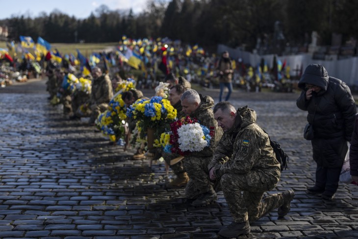 Ukrán katonák térdepelve vesznek búcsút parancsnokuktól, Oleg Vojtyuktól a nyugat-ukrajnai Lviv temetőjében 2023. február 21-én. Vojtyuk a Bahmut településért vívott harcokban szerzett halálos sérülést. Fotó: MTI/AP/Pétrosz Jannakurisz 