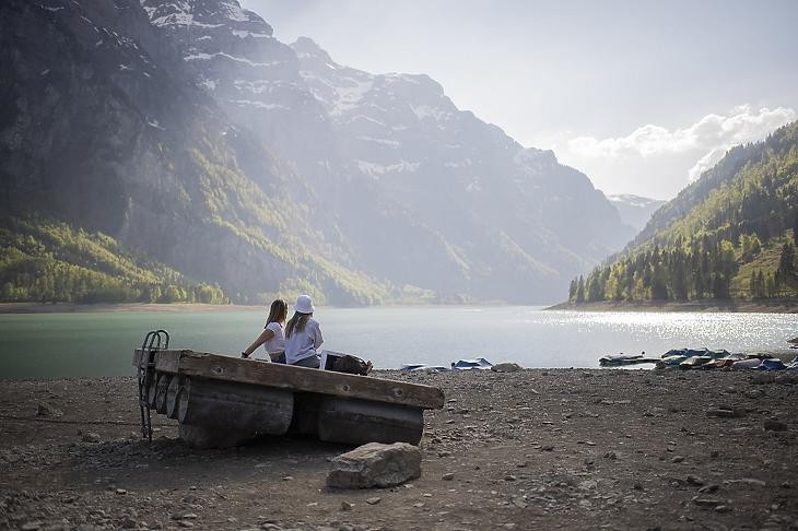 A klímaváltozás egyre szembetűnőbb: kirándulók az alacsony vízszintű Klöntali-tó partján Svájcban. Fotó: MTI/EPA/Keystone/Gian Ehrenzeller