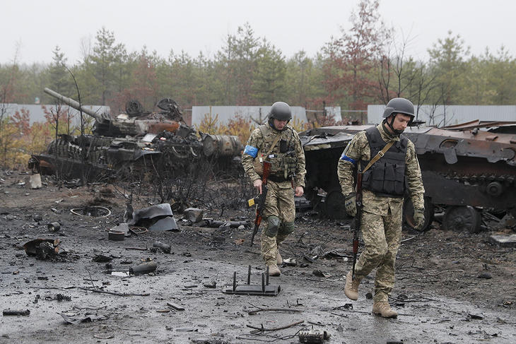 Ukrán katonák egy megsemmisült orosz páncélozott harci jármű roncsa előtt a Kijev megyében fekvő és az ukrán hadsereg által visszafoglalt Dmitrivkában. Fotó MTI/EPA/Szerhij Dolzsenko
