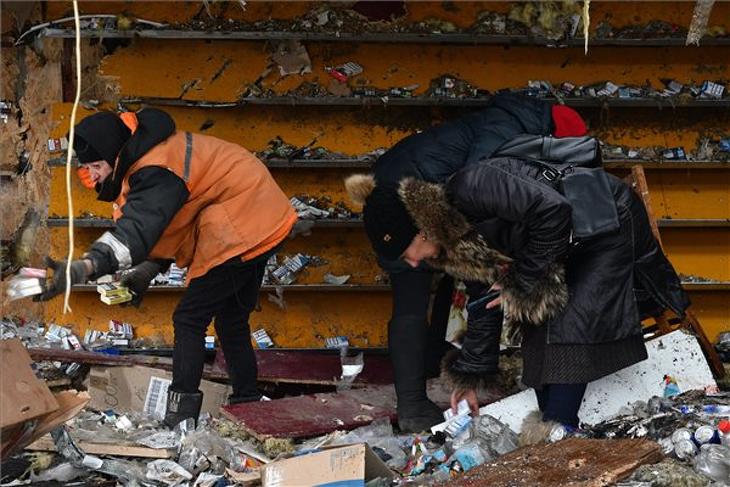 Egy üzlet romjai közül szednek össze cigarettát ukránok a kelet-ukrajnai Donyecki területen fekvő Kurahovéban egy előző napi orosz tüzérségi támadás után, 2022. december 8-án. Fotó: MTI/AP/Andrij Andrijenko