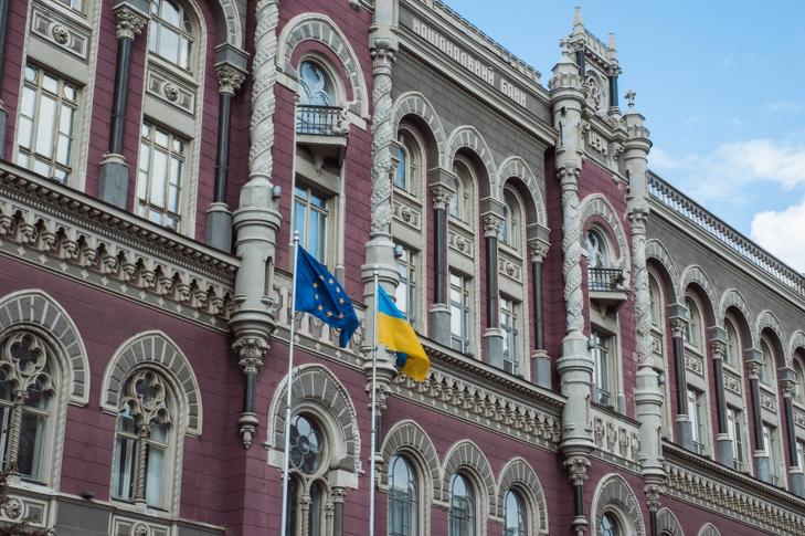 Az Ukrán Nemzeti Bank főépülete, előtérben az Európai Unió és Ukrajna zászlója. Az EU és az IMF is elvárja a pénzügyi rendszer átláthatóvá tételét és további liberalizálását