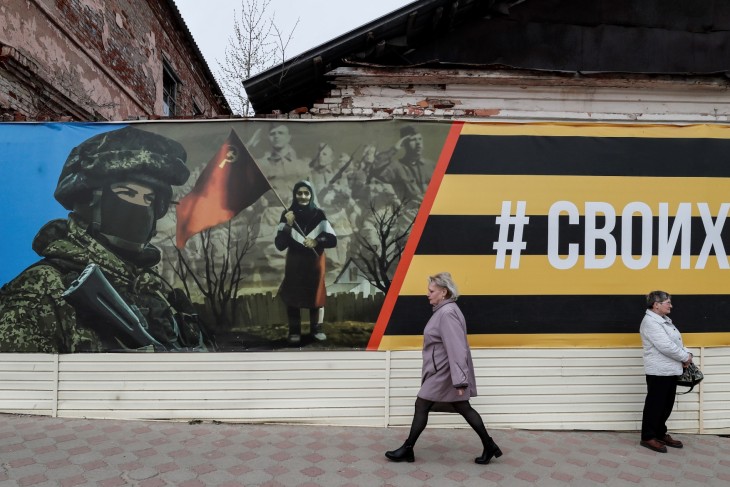 Emberek egy háborús plakát előtt a Jefremov nevű orosz városban 2023. április 20-án. Fotó: EPA/YURI KOCHETKOV 