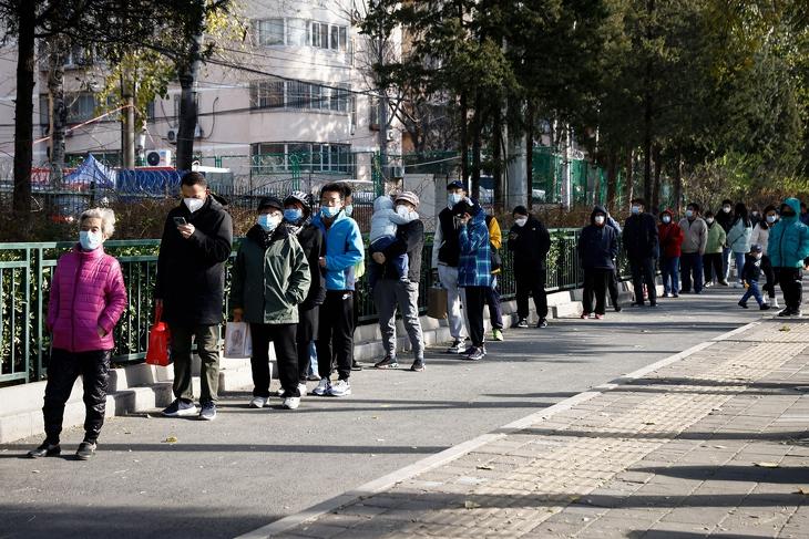 Belefáradtak. Covid-tesztre várakozó emberek Pekingben 2022. november 26-án. EPA/MARK R. CRISTINO