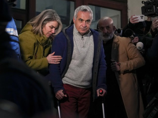 Calin Georgescut, a romániai elnökválasztás november 24-i első fordulójában legtöbb szavazatot szerző független jelöltet a felesége, Cristela kíséri, amint távozik a legfőbb ügyészség bukaresti épületéből 2025. február 26-án. 