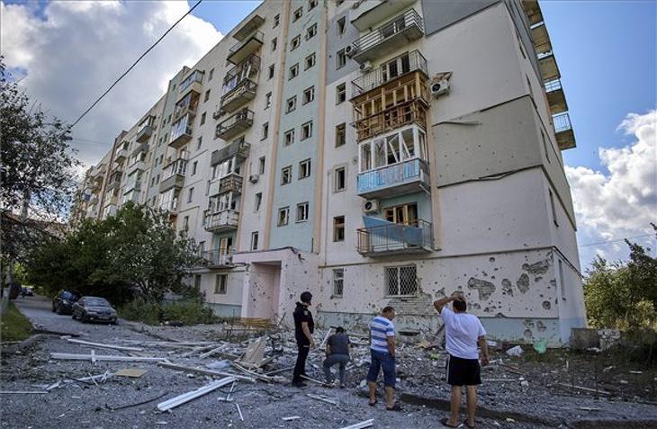 Megrongált lakóház előtt helybeliek és egy rendőr Harkivban. MTI/EPA/SERGEY KOZLOV