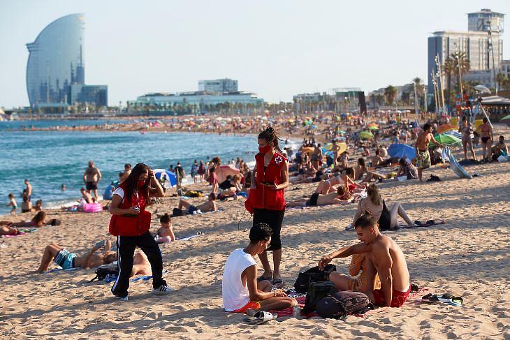 A Vöröskereszt aktivistái figyelmeztetik a strandolókat a járványveszélyre Barcelonában 2020. auguaztua hetedikén. EPA/Alejandro Garcia