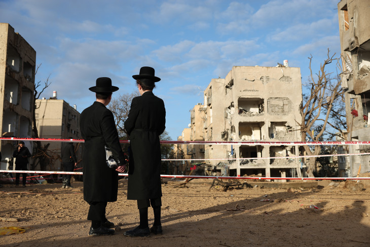 Ultraortodox zsidó lakosok nézik az iráni rakétatámadásban megrongálódott lakóépületeket a dél-izraeli Arad városban 2026. március 22-én