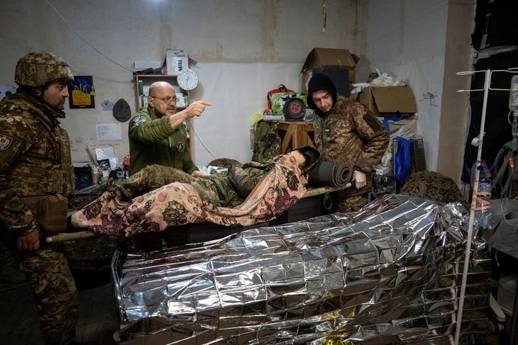 Az a sebesült, aki már legalább egy tábori kórházig eljut, annak máris jobbak az esélyei - Sebesült ukrán katonát állnak körül bajtársai egy tábori kórházban az ukrajnai háború frontvonalánál, a Donyeck megyei Bahmut térségében 2023. február 26-án. Fotó: MTI/AP