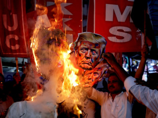 Indiai ellenzéki aktivisták Donald Trump amerikai elnök gúnymaszkját égetik tiltakozásul az Indiára kivetett amerikai büntetővámok miatt
