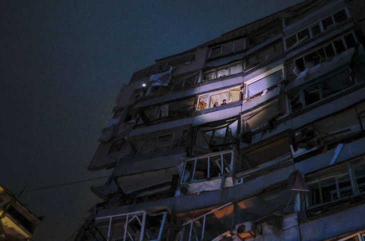 A mentők segítségét várva néznek ki lakók egy ablakon az ukrajnai Dnyipróban 2023. január 14-én, miután orosz rakétatalálat ért a házukat. Fotó: MTI/AP