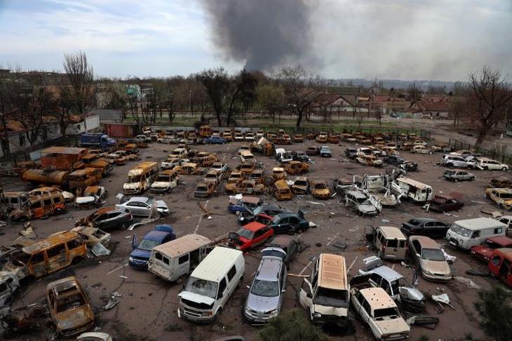 Megrongálódott és kiégett járművek az Iljics Acél- és Vasművek területén, miközben füst száll fel az Azovsztal acélgyár területéről Mariupolban 2022. április 18-án. Fotó: MTI/AP
