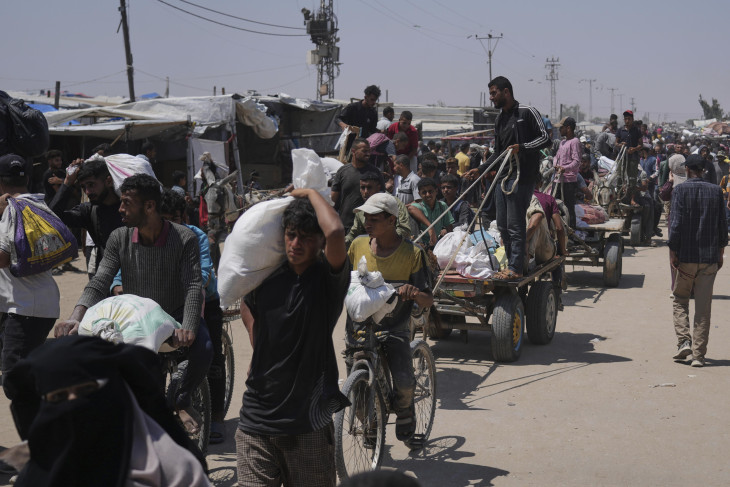 Az amerikai hátterű Gázai Humanitárius Alap segélyszervezet által kiosztott, élelmiszert és egyéb segélyt tartalmazó zsákokat cipelnek palesztinok a Gázai övezet déli részén fekvő Rafahban 2025. június 16-án. 