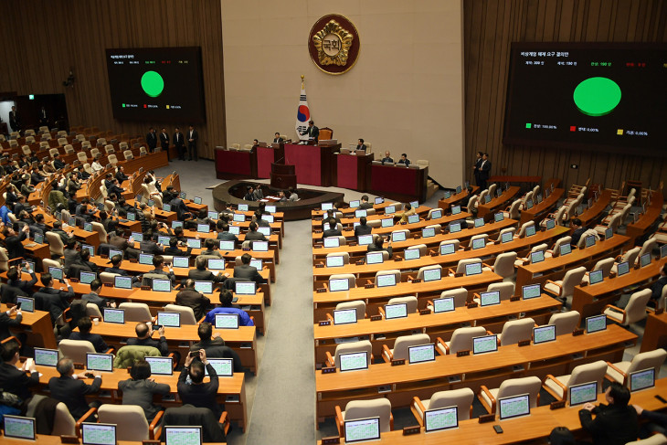 A kormányzó és az ellenzéki pártok képviselői egyhangúlag a dél-koreai elnök által előző nap kihirdetett szükségállapot visszavonását sürgető határozatot szavaznak meg a parlament szöuli üléstermében 2024. december 4-én hajnalban