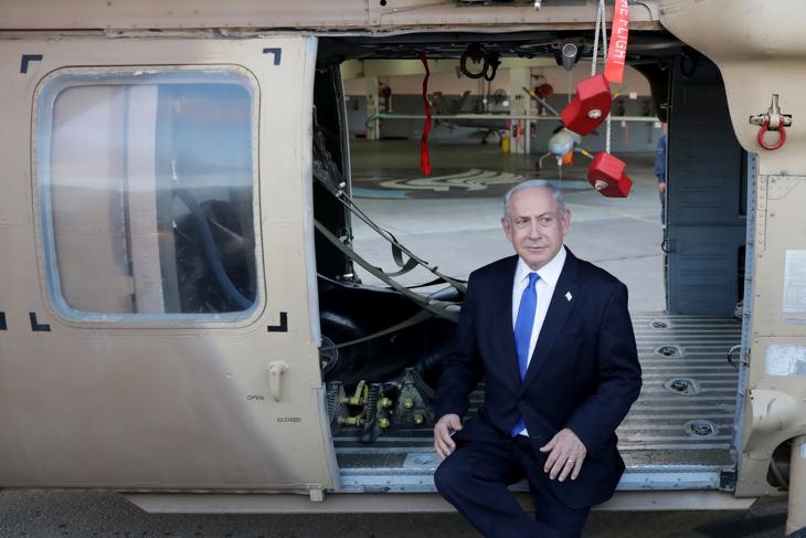 Benjámin Netanjahu izraeli miniszterelnök egy katonai szállítóhelikopter ajtajában ül egy izraeli légibázison tett korábbi látogatáson, 2023. július 5-én. Fotó: MTI/EPA/Abir Szultan 