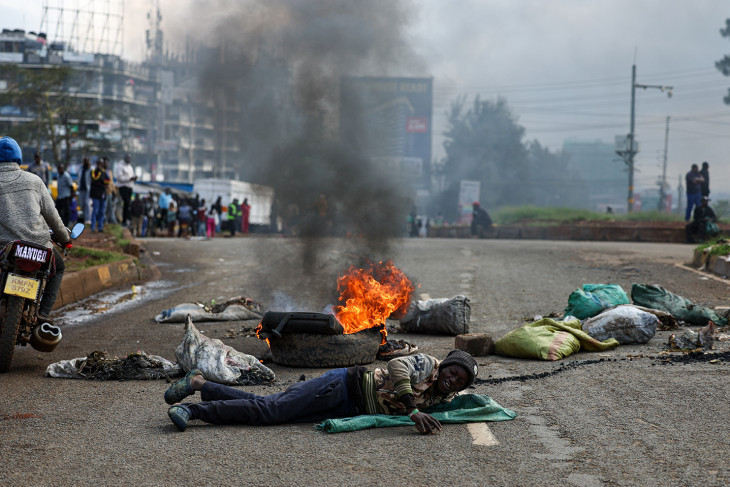 Lángoló útakadálynál fekszik egy tüntető az üzemanyagárak emelkedése miatt meghirdetett országos közlekedési sztrájk és tiltakozóakciók idején a kenyai főváros, Nairobi Roysambu nevű külvárosában 2026. május 18-án