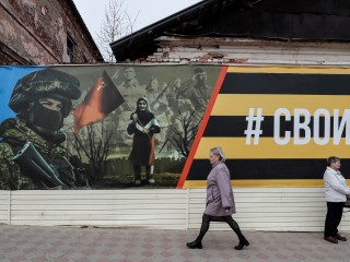 Emberek sétálnak el egy háborús plakát előtt  a Jefremov nevű orosz városban  2023. április 20-án. Fotó: EPA/YURI KOCHETKOV  