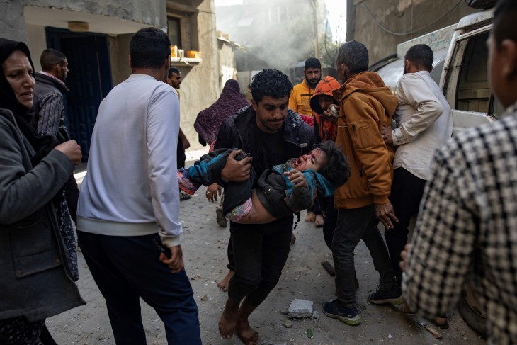 Egy sebesült gyereket visz egy férfi egy izraeli légicsapás után Deir al-Balah táborban a Gázai övezetben 2024. március 9-én.