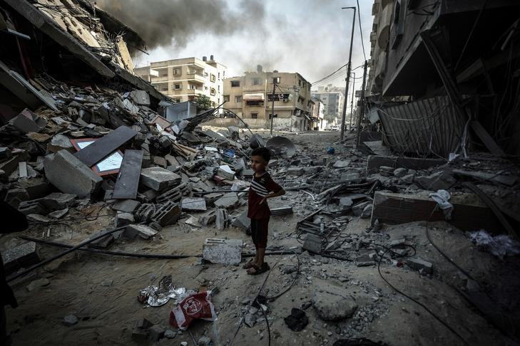 Egy kisfiú áll a romok közt Gázában az izraeli légicsapások után. Fotó: Twitter/UNRWA (az ENSZ palesztin menekültekkel foglalkozó ügynöksége) 