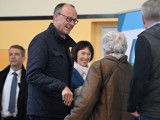 Friedrich Merz, a Kereszténydemokrata Unió (CDU) elnöke, a CDU és bajor testvérpártja, a Keresztényszociális Unió (CSU) közös jelöltje (b) a helyi emberekkel beszéget, mielőtt leadja szavazatát a németországi előrehozott szövetségi parlamenti választáson az Észak-Rajna-Vesztfália tartományban lévő Arnsbergben 2025. február 23-án. 