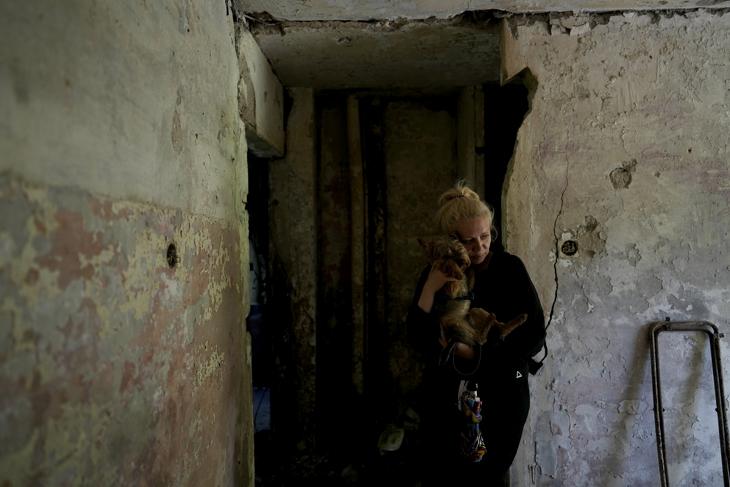 Ukrán nő kutyájával megsemmisült lakása egyik helyiségében a Kijev közelében lévő Irpinyban 2022. május 26-án. Fotó: MTI/AP/Natacha Pisarenko