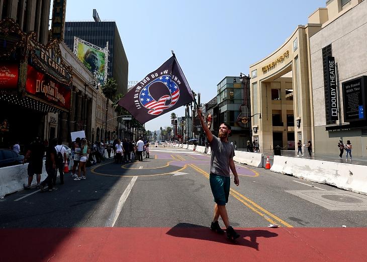 A QAnon csoport zászlaját lengető tüntető 2020. augusztusában Hollywoodban. A csoport egyebek mellett azt terjeszti, hollywoodi színészek gyerekek ellen követnek el bűncselekményeket. Fotó: EPA / Christian Monterrosa