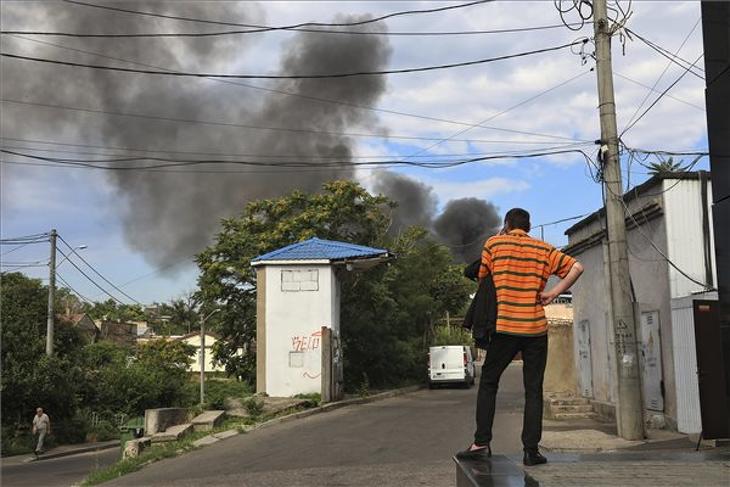Férfi telefonál, miközben füst száll fel a fekete-tengeri kikötőváros, Odessza felett egy orosz tüzérségi támadást követően 2022. július 16-án. MTI/AP/Nina Lyashonok