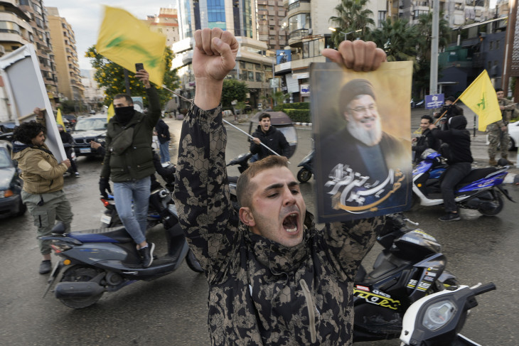 Haszan Naszralláh sejknek, a Hezbollah libanoni Irán-barát síita szervezet Izrael által meggyilkolt vezetőjét ábrázoló képpel és Hezbollah-zászlókkal ünneplik az Izrael és a Hezbollah közötti tűzszüneti megállapodást emberek Bejrút túlnyomórészt síiták lakta déli elővárosában, Dahijében 2024. november 27-én
